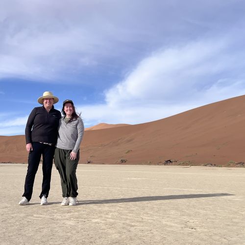 Two women standing in front of a dune.