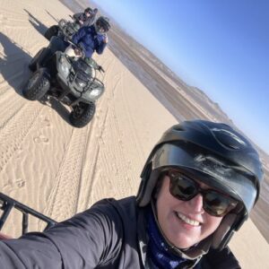 A woman taking a selfie while on a quad bike in the desert.