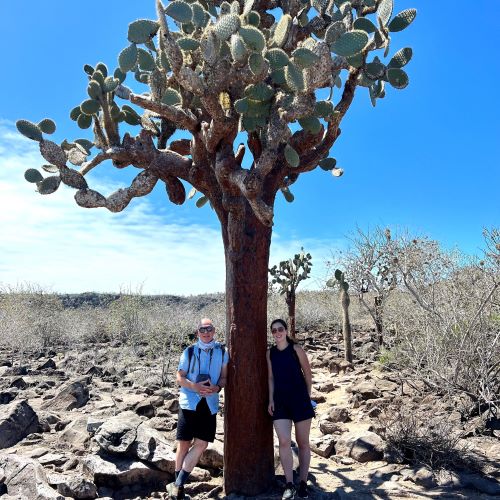 Two people standing by a cactus tree in the Galapagos Island