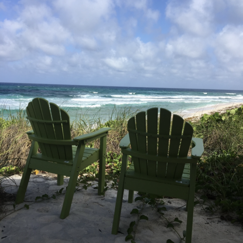 Two chairs on an ocean beach.