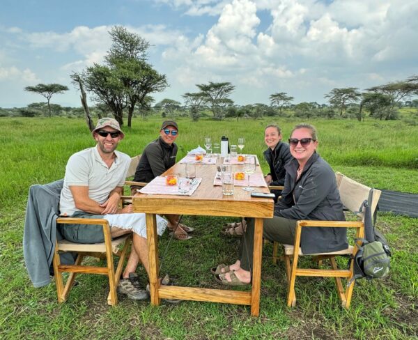 Four people enjoy an outdoor lunch in Tanzania's Serengeti National Park.