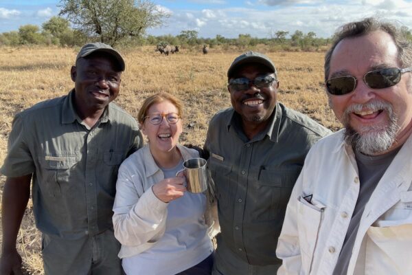 Guests with their safari guides and rhinos in the background.