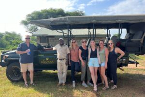 A group of people standing by a safari vehicle.