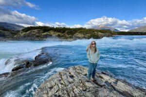 Woman standing on rocks by water.