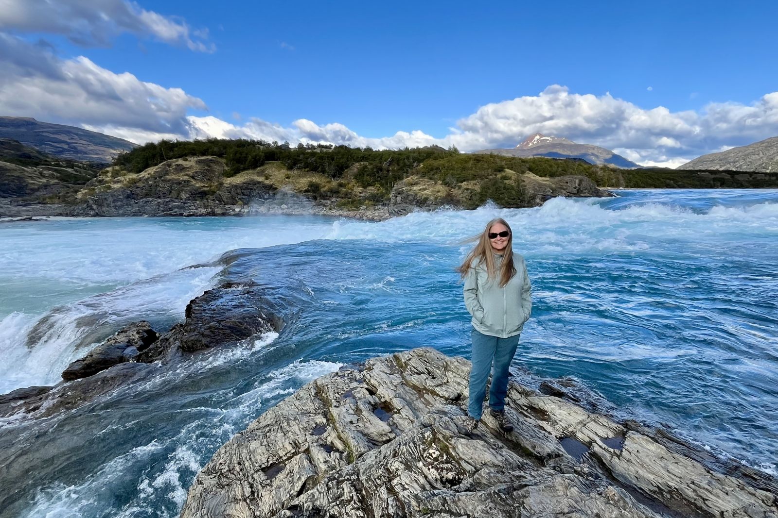 Woman standing on rocks by water.