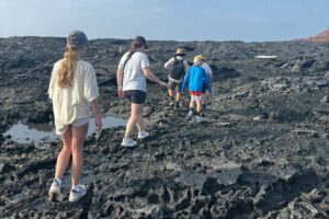 Tourists walking on a black lava area.