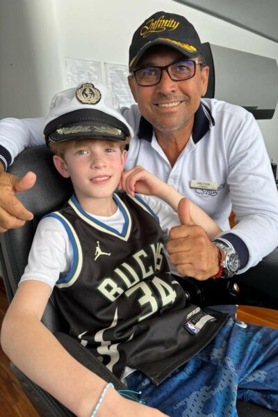 A boat captain with a young boy wearing his hat.