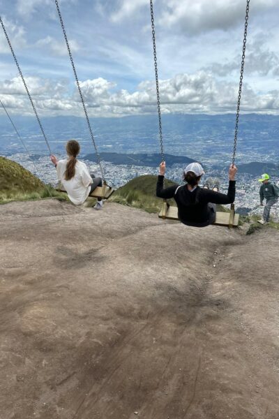 Two children swinging while overlooking Quito, Ecuador.