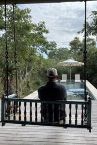 Person sitting on a swing overlooking the pool.