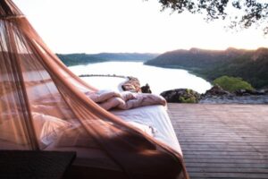 View of an outdoor bed and pool overlooking the water.