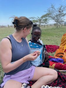 A traveler being taught the traditional art of beading from a Maasai woman.