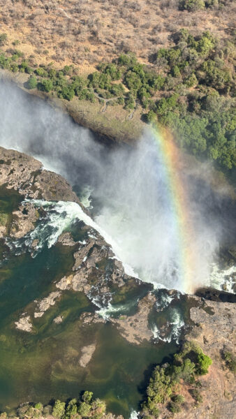 An overhead view of Victoria Falls with a rainbow in the mist.